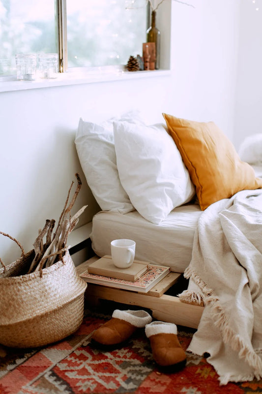 Bed with a nigh stand that has two books and a coffee on top